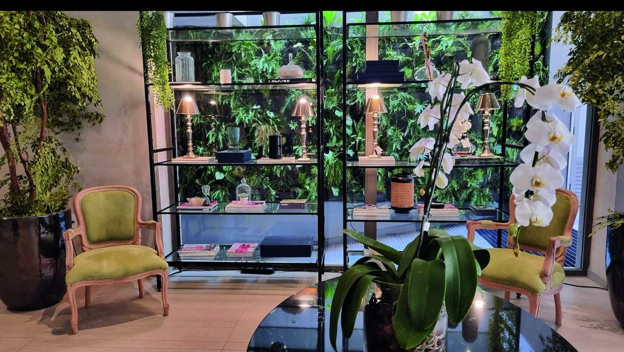 Lounge com jardim vertical, poltronas verdes e luz natural
